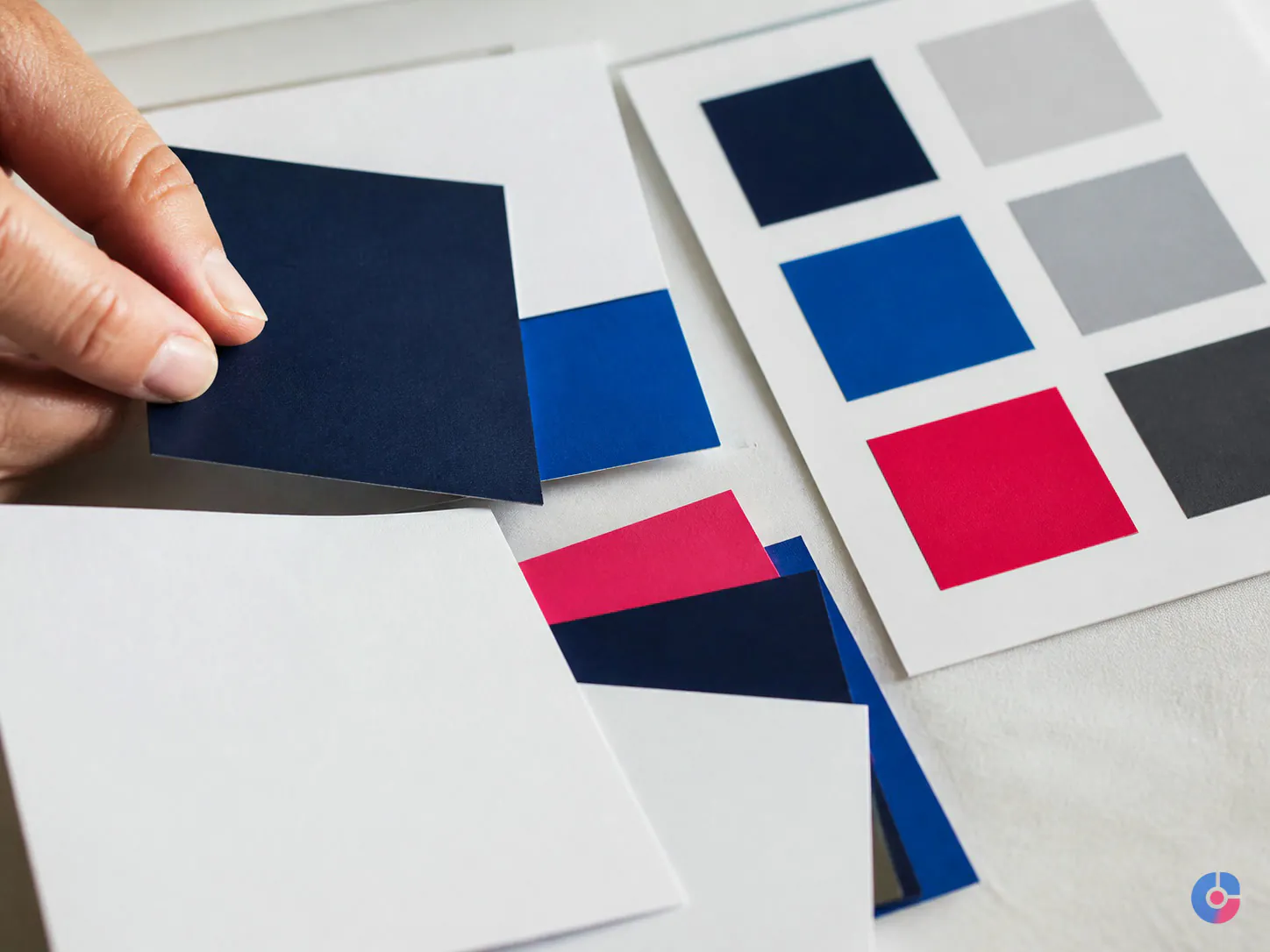 Printed brand colour chips being checked for contrast on a designer's desk