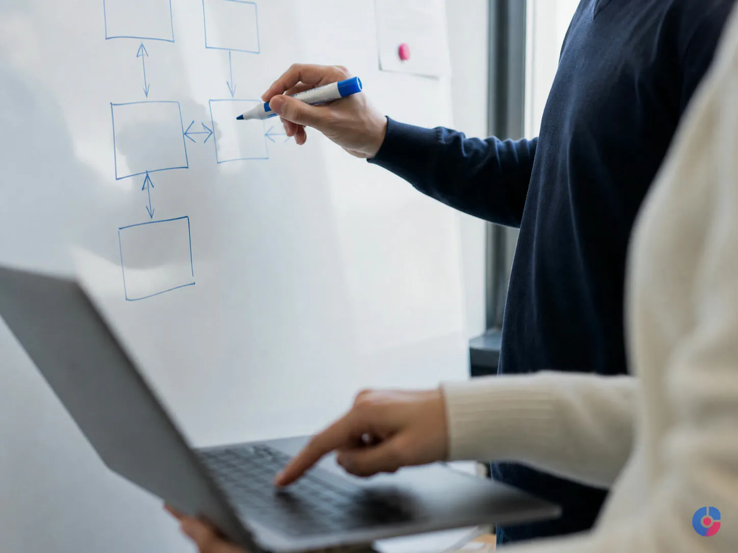 Two colleagues agreeing database record definitions at a whiteboard during a review session