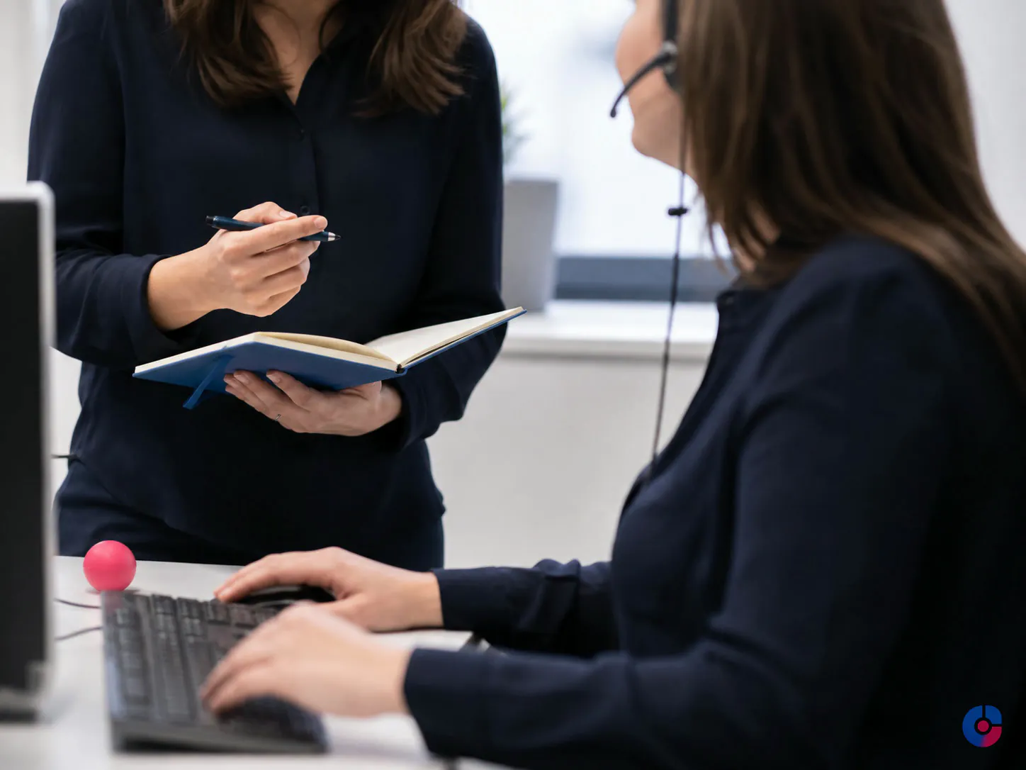 Two support agents completing a shift handover briefing beside a workstation at dawn